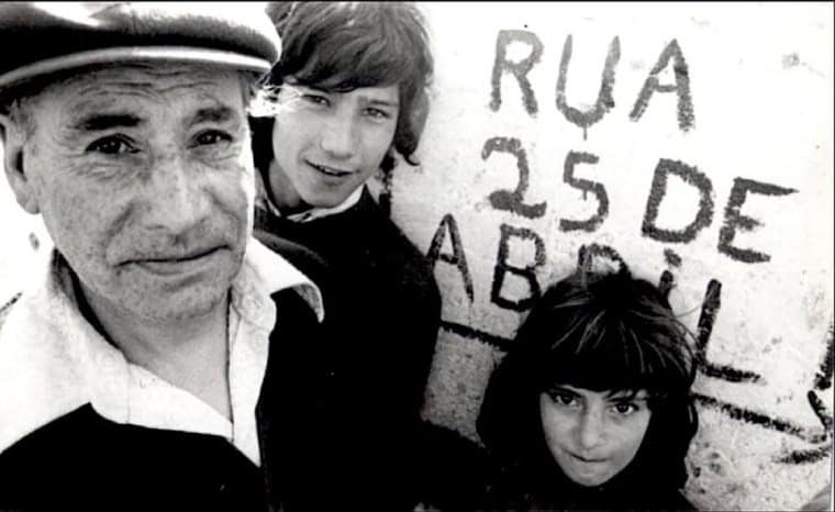 trois personnes à côté d'un nom de rue changé pendant la Révolution portugaise