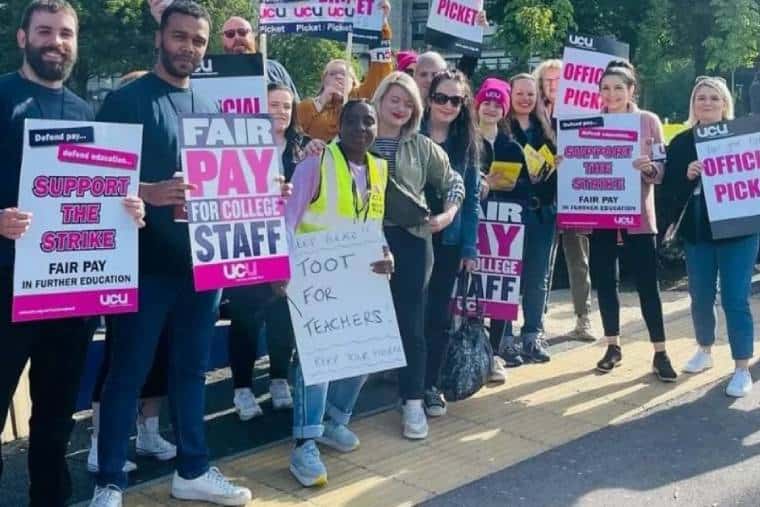 Further education workers hold up signs saying