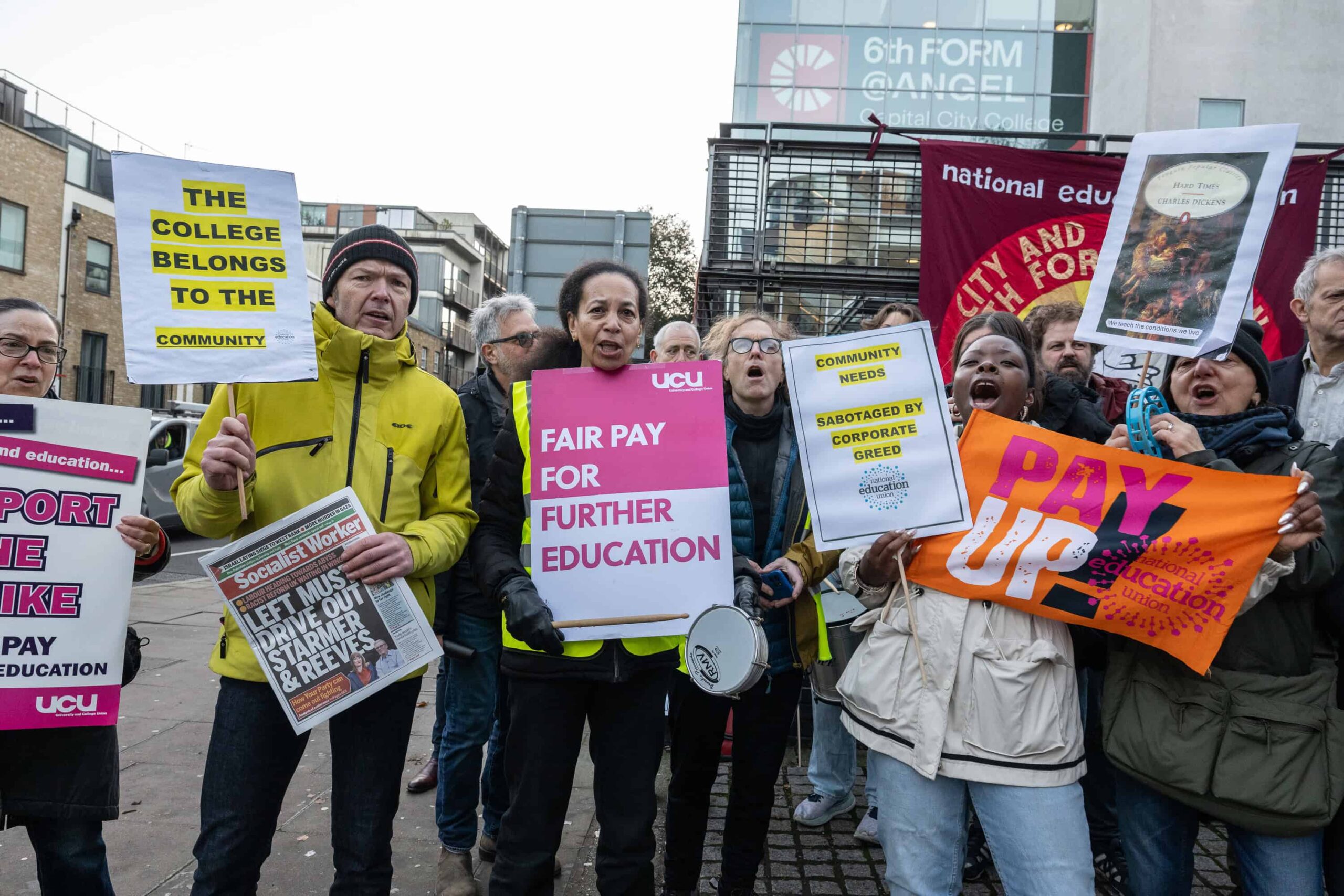 UCU and NEU union members on the picket line during the London college strike. They hold up signs and photographed while chanting.