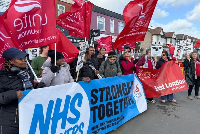 Crowd of strikers with Unite flags and NHS stronger together banner