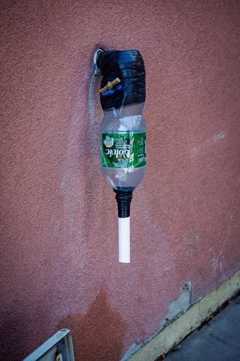 Un robinet de fortune fabriqué à partir d'une bouteille en plastique collée sur le bâtiment (Photo : Dave Gilchrist)