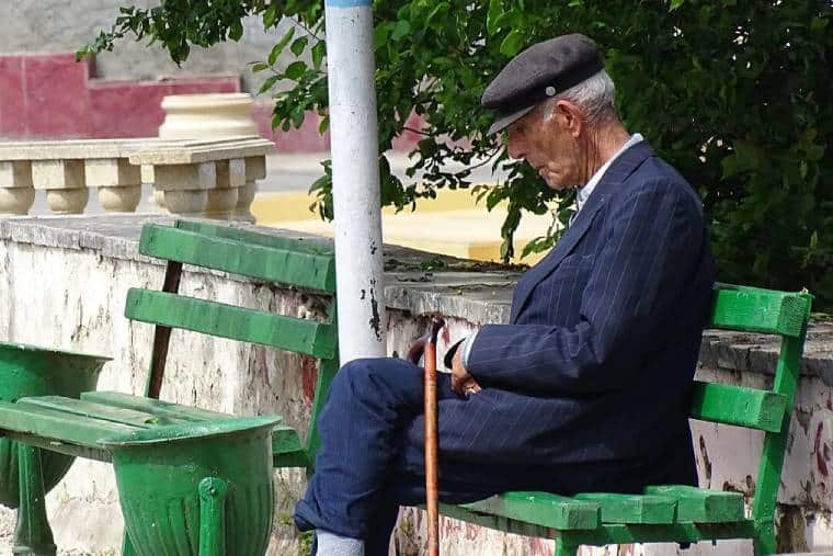 An elderly man is sitting on a bench to accompany an article about pensions