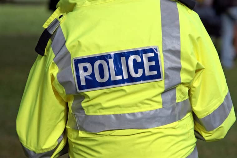 Image de dos d'un policier en service désigné portant une veste haute visibilité